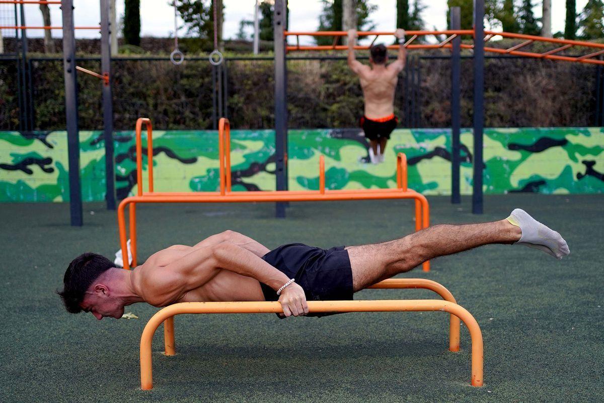 Dos adolescentes musculan su cuerpo en un parque público de Madrid.