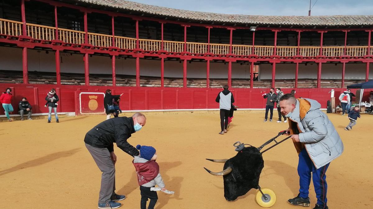 Un niño acompañado por su abuelo frente a un astado en la plaza de toros