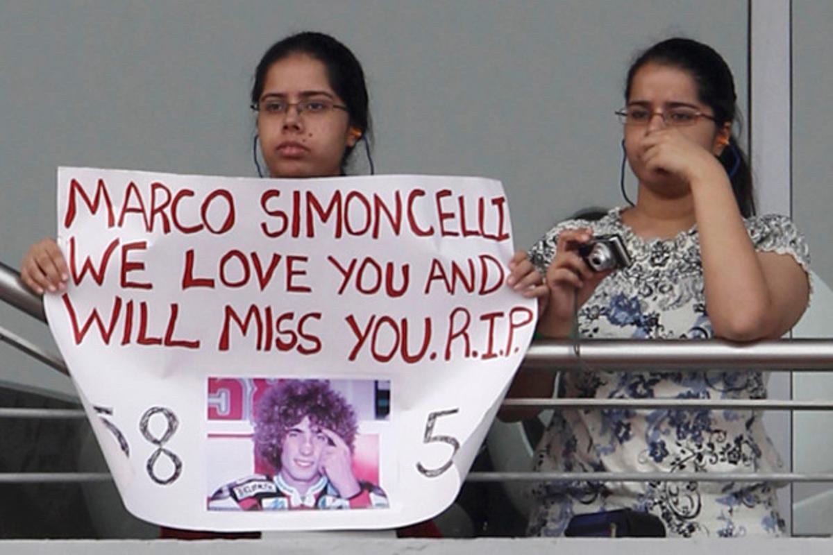 Una noia amb una pancarta amb la foto del motorista Marco Simoncelli mentre observa el primer entrenament del GP de fórmula 1 als afores de Nova Delhi.