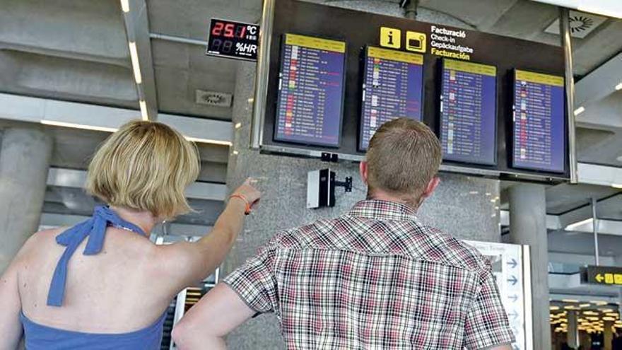 Dos pasajeros consultan el panel de horarios.