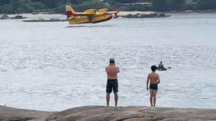 Dos bañistas viendo el amerizaje del hidroavión.