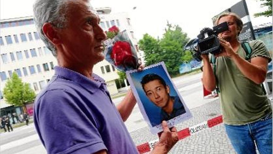 Un home mostra una fotografia del seu fill, que va morir assassinat en l&#039;assalt al centre comercial.