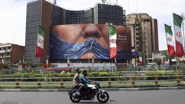 Dos homes passen davant d’un cartell amb el rostre segmentat de Donald Trump, ahir a Teheran.  |  ABEDIN TAHERKENAREH / EFE / EPA