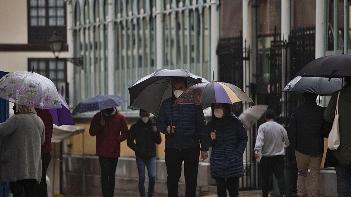 Vecinos de Oviedo, paseando bajo el paraguas por el centro de la capital.