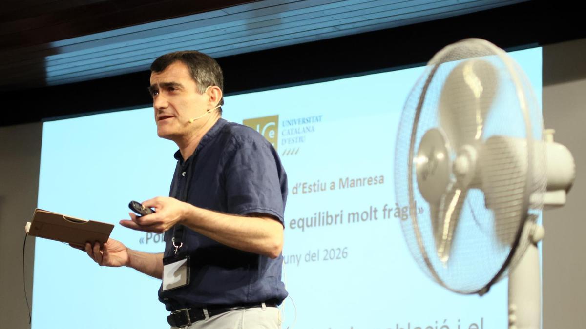 Intervenció de l'economista Xavier Cuadras en la taula rodona sobre "El creixement de la població i els recursos"; en primer terme, un dels ventiladors que han posat a la sala