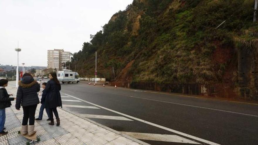 Un grupo de personas en el paseo marítimo y a la derecha los restos del argayo de ayer en la avenida de Juan Sitges de Salinas.