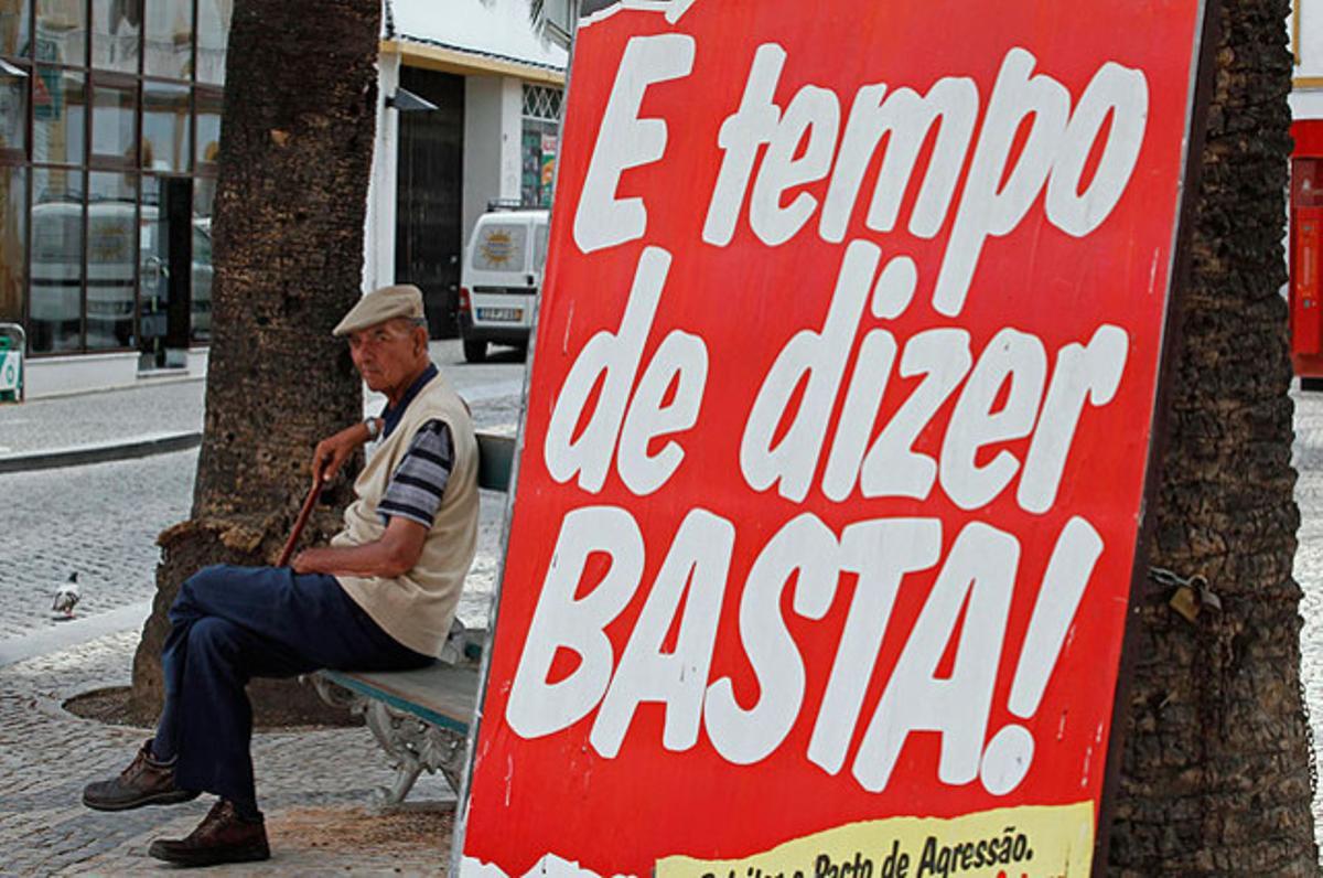 Un pensionista seu al costat d’una pancarta que diu: Ja és hora de dir prou, al poble de Grandola (sud de Portugal), mentre el país pateix la pitjor ratxa econòmica de la seva història recent.