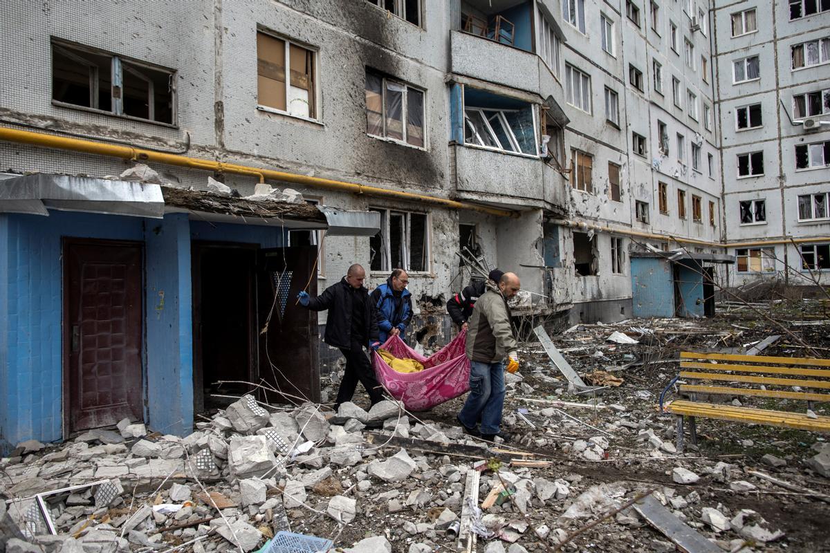 Los trabajadores de emergencia llevan el cuerpo de una mujer después de un ataque de artillería, en medio del ataque de Rusia contra Ucrania, en Kharkiv, Ucrania.