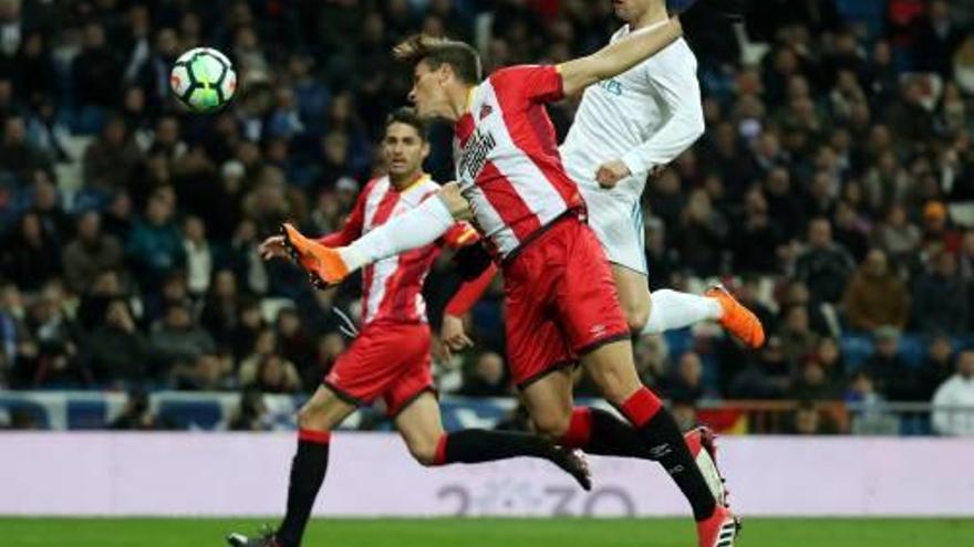 Cristiano Ronaldo, que marcó cuatro goles, intenta conectar un remante anoche en el Bernabéu entre dos defensores del Girona.
