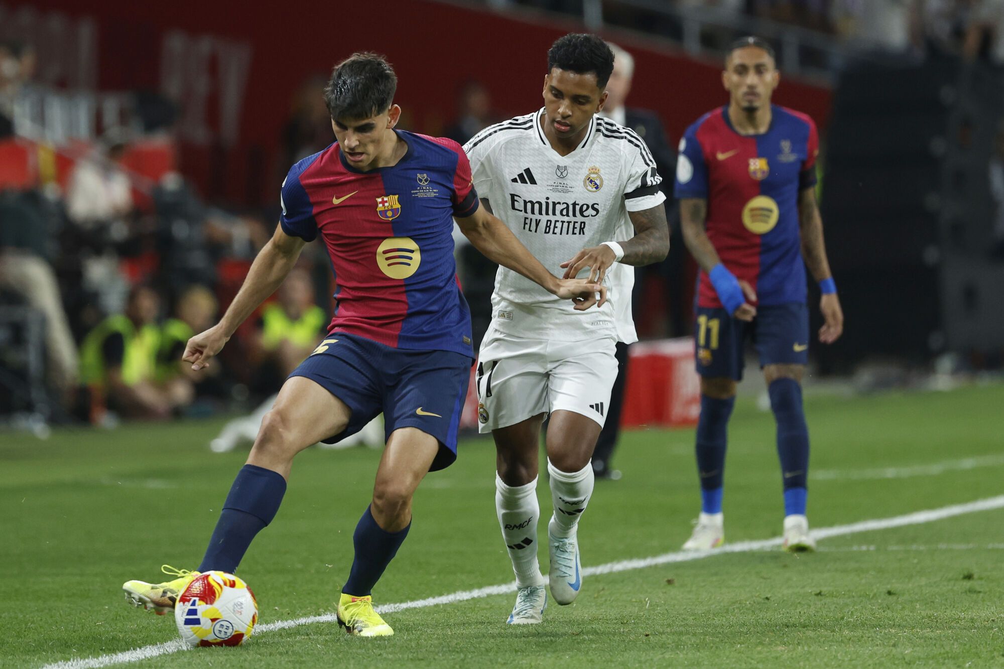 Barcelona's Gerard Martin, left, is challenged by Real Madrid's Rodrygo during the Spanish Copa del Rey final soccer match between Barcelona and Real Madrid at Estadio de La Cartuja stadium in Seville, Spain, Saturday, April 26, 2025. (AP Photo/Joan Monfort)