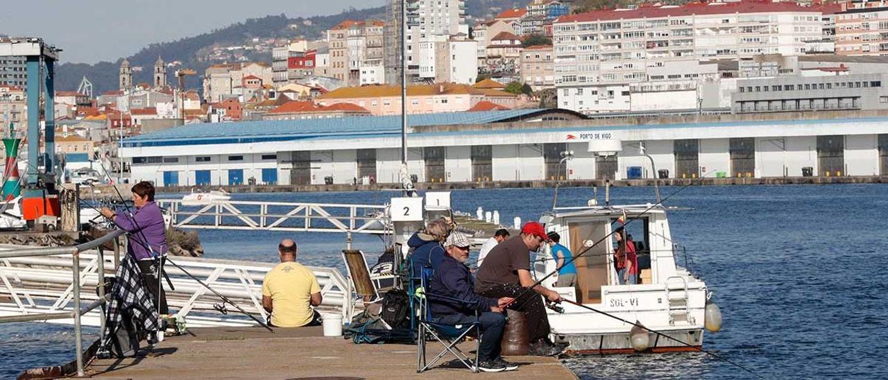 Pescadores recreativos, con un barco al fondo, en Vigo.