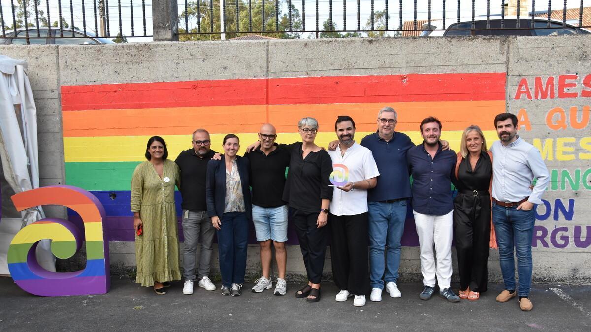 Membros da Corporación de Ames e o premiado pola mellor fotografía, sostendo o trofeo, coa bandeira multicor do orgullo e o lema