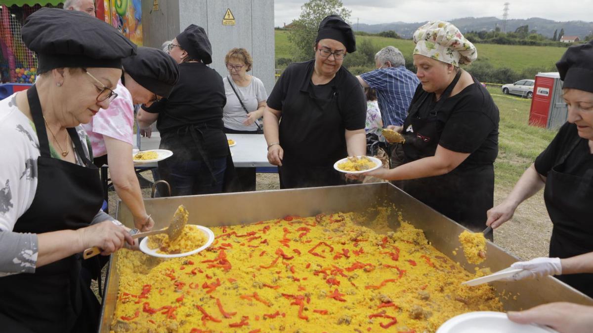 Varias colaboradoras sirven  raciones de paella en platos. | Fernando Rodríguez