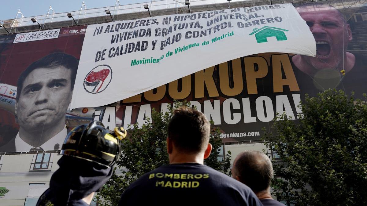 El cartel de Desokupa en la calle Atocha de Madrid, tapado por una pancarta en la que se lee ‘Ni alquileres, ni hipotecas, ni deudas. Vivienda gratuita, universal, de calidad y bajo control obrero’.