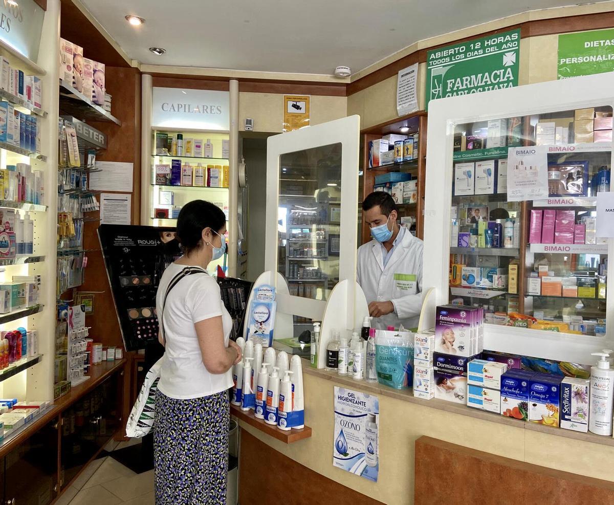 Francisco Criado atiende a una clienta en su farmacia, ubicada en la avenida Carlos Haya