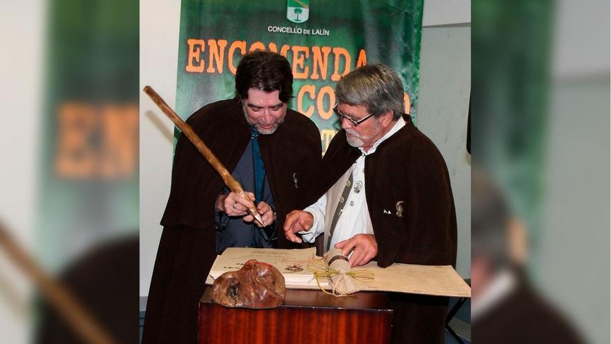 Paco Lareo indica ao cantautor Joaquín Sabina onde ten que firmar co estadullo, tamén obra súa, logo de ser investido comendador da Feira do Cocido.