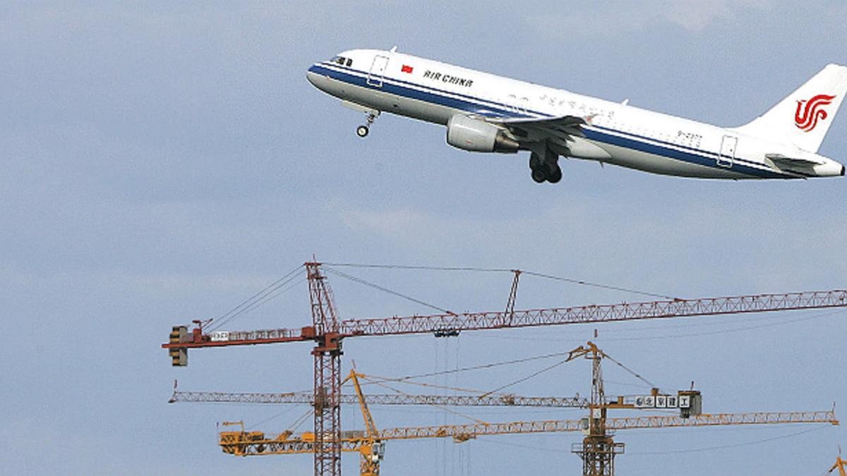 Un avión de Air China sobrevuela unas grúas en Pekín.