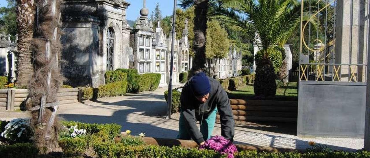 Un hombre coloca flores en el cementerio de Ponteareas. // FdV