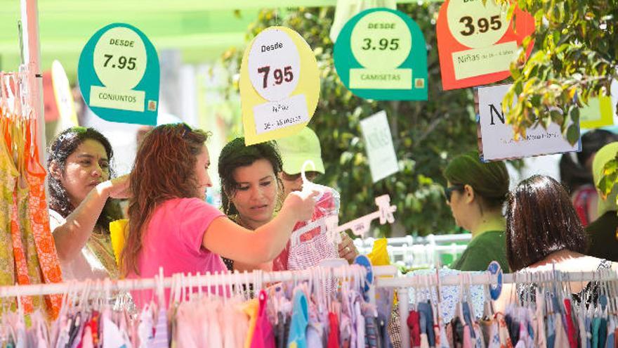 Un comercio de ropa infantil cuelga carteles con descuentos en la feria.