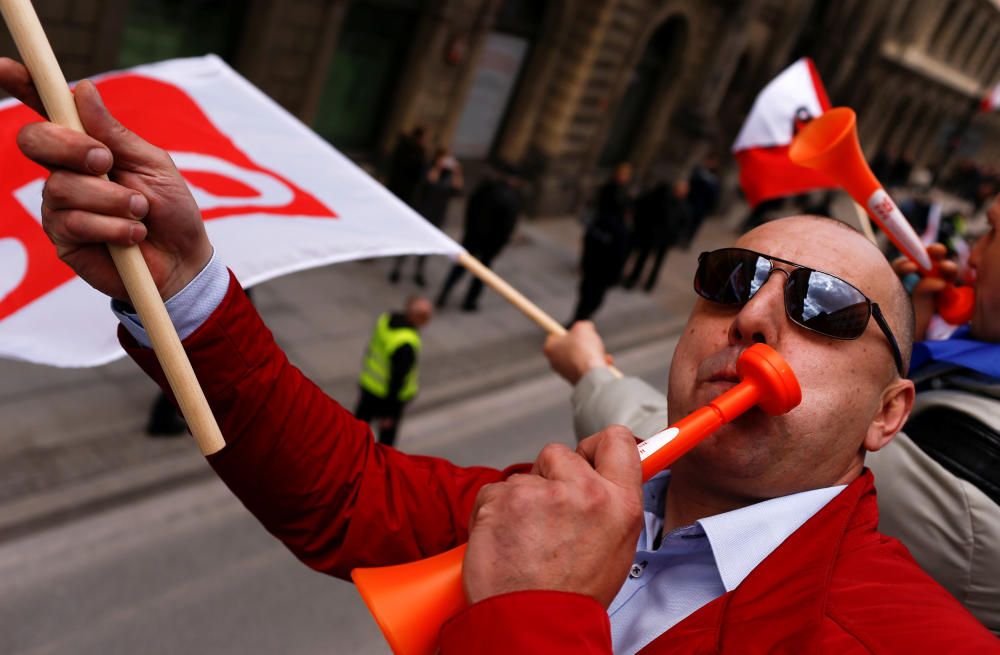 A man blows a horn during the May Day rally in ...