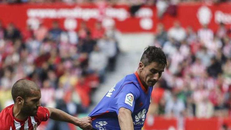 Saúl Berjón aguanta la pelota ante Lora, ayer en El Molinón.