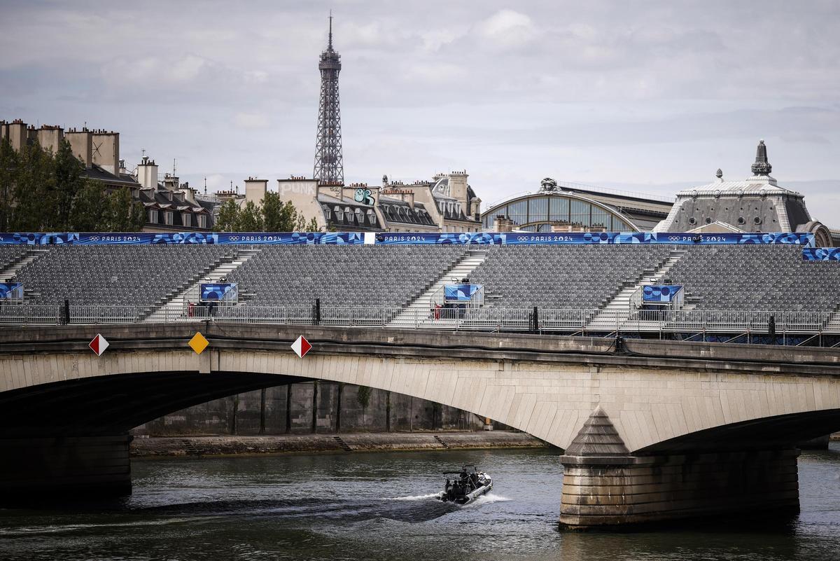 Una lancha navega por el río Sena con las gradas preparadas para la ceremonia de inauguración de los Juegos Olímpicos en París