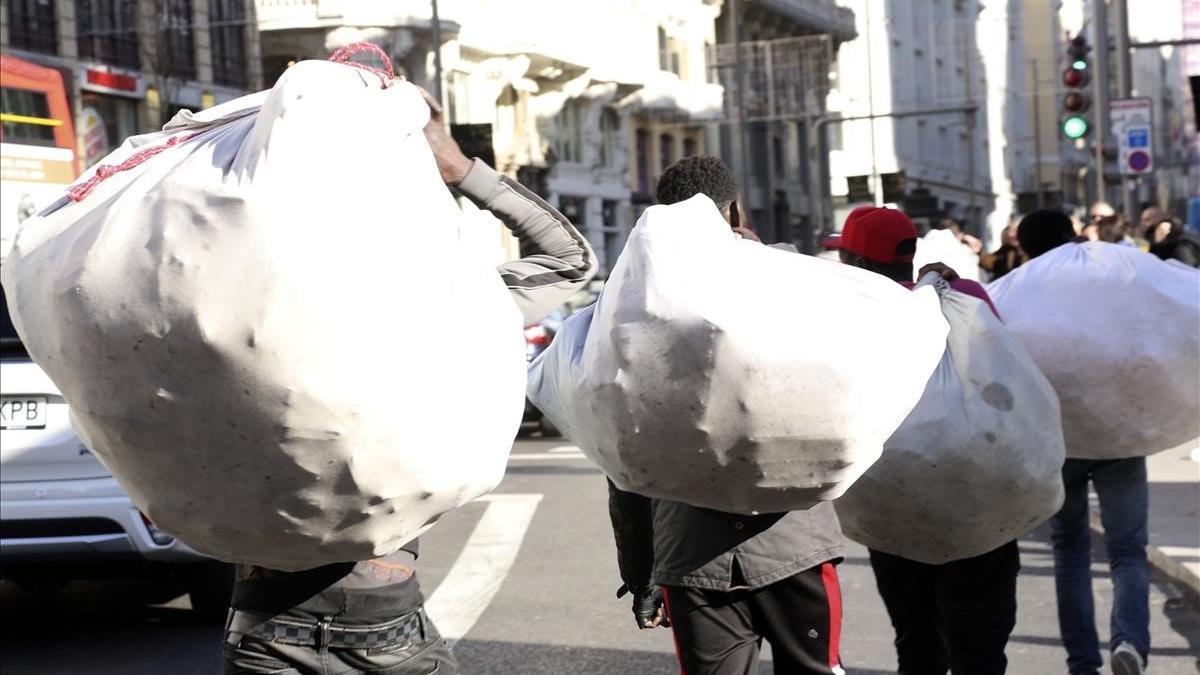 Manteros senegaleses camino de sus lugares en la Gran Vía de Madrid