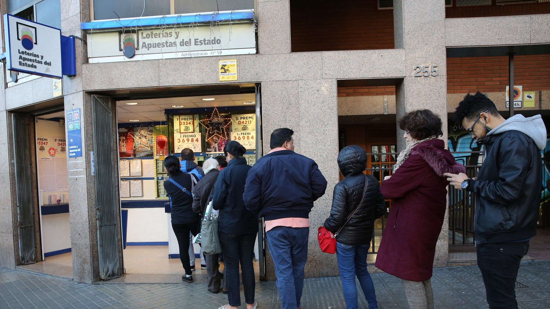 Varias personas hacen cola para comprar Lotería de Navidad en una administración de Barcelona