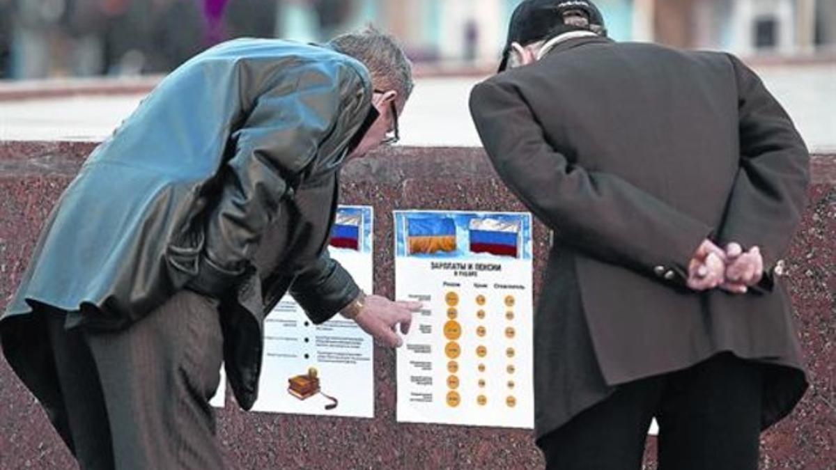 Dos hombres leen dos carteles electorales en una plaza de Simferópol.