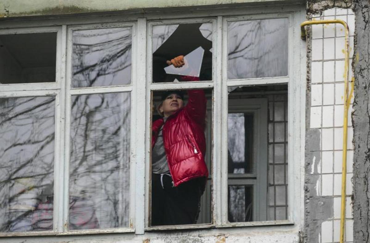 Una mujer retira cristales rotos de una ventana de su vivienda en Odesa.
