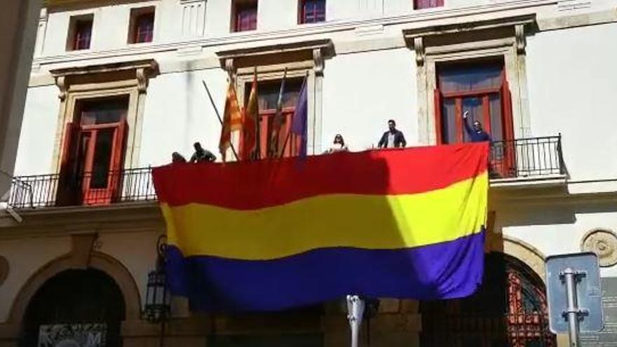 Las concejalas Roser Maestro y María Giménez con miembros de EU al ondear la bandera.