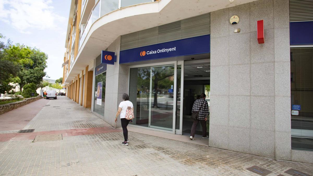 Dos vecinos, frente a las oficinas que Caixa Ontinyent ha vendido al Ayuntamiento y serán un punto social.