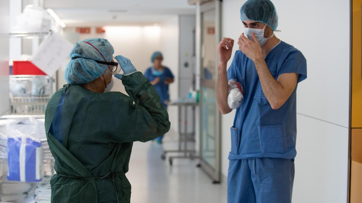 Un professional sanitari ajuda una companya a protegir-se abans d&#039;atendre un pacient amb covid-19.