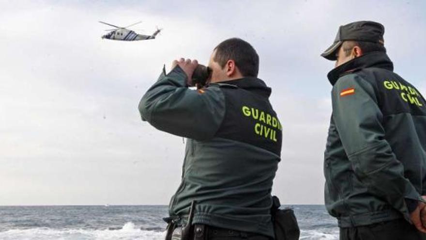 El helicóptero &#039;Pesca 1&#039;, al fondo, durante la búsqueda de la percebeira fallecida el miércoles. / marta g. brea