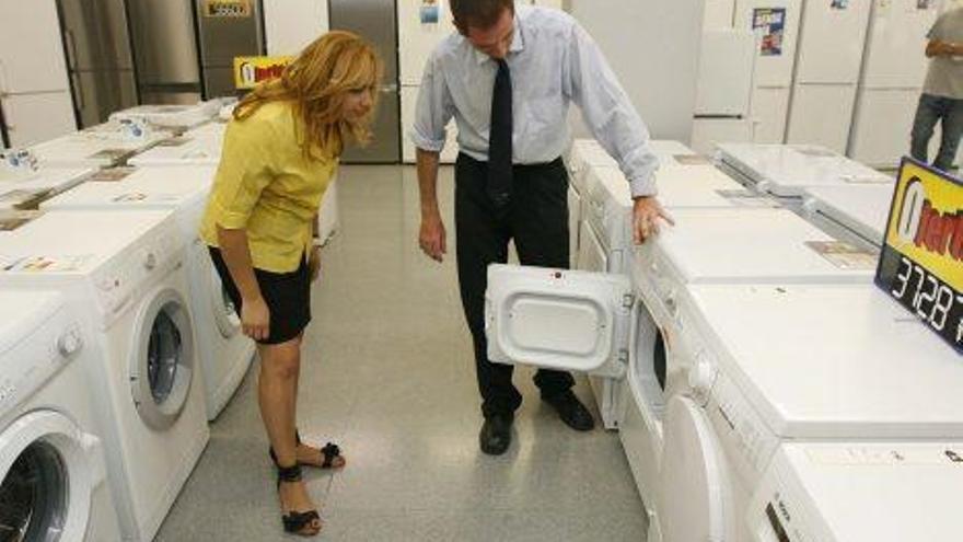 Un venedor mostra una rentadora a una clienta, en una botiga d&#039;electrodomèstics