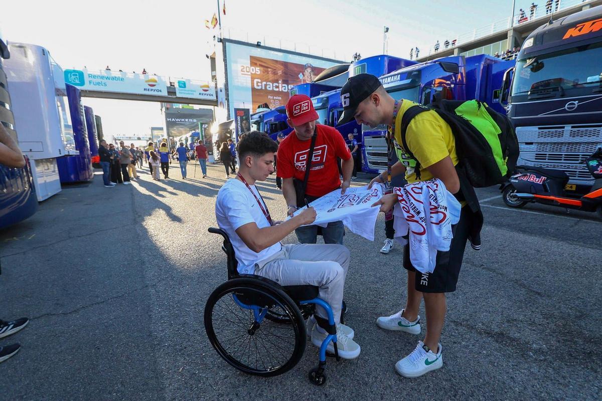 Carlos Tatay firma autógrafos a dos aficionados en el paddock de Cheste