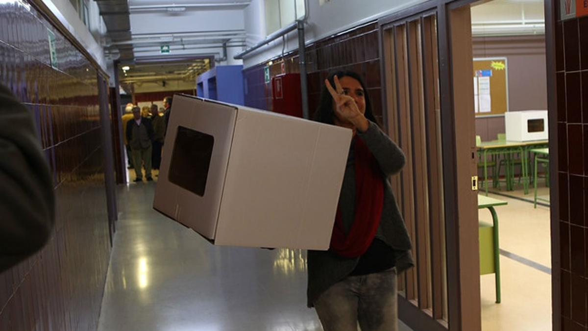 Una voluntaria hace el signo de la victoria antes de abrir el punto de participación, en Girona.