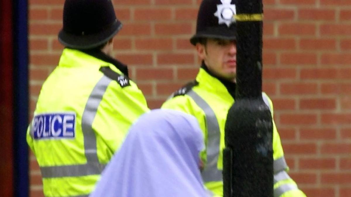 Una mujer musulmana pasa junto a dos policías británicos.