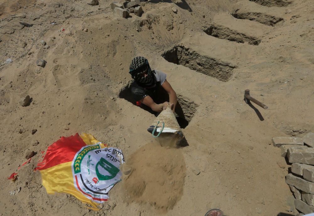 Un hombre cava tumbas para combatientes chiítas iraquíes conocidos como Kattaib Sayeed al-Shuhadaa que fueron asesinados cerca de la frontera siria, durante el funeral en Najaf, Irak Agosto