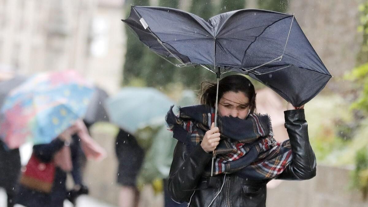 Una joven pelea contra el viento para mantener su paraguas