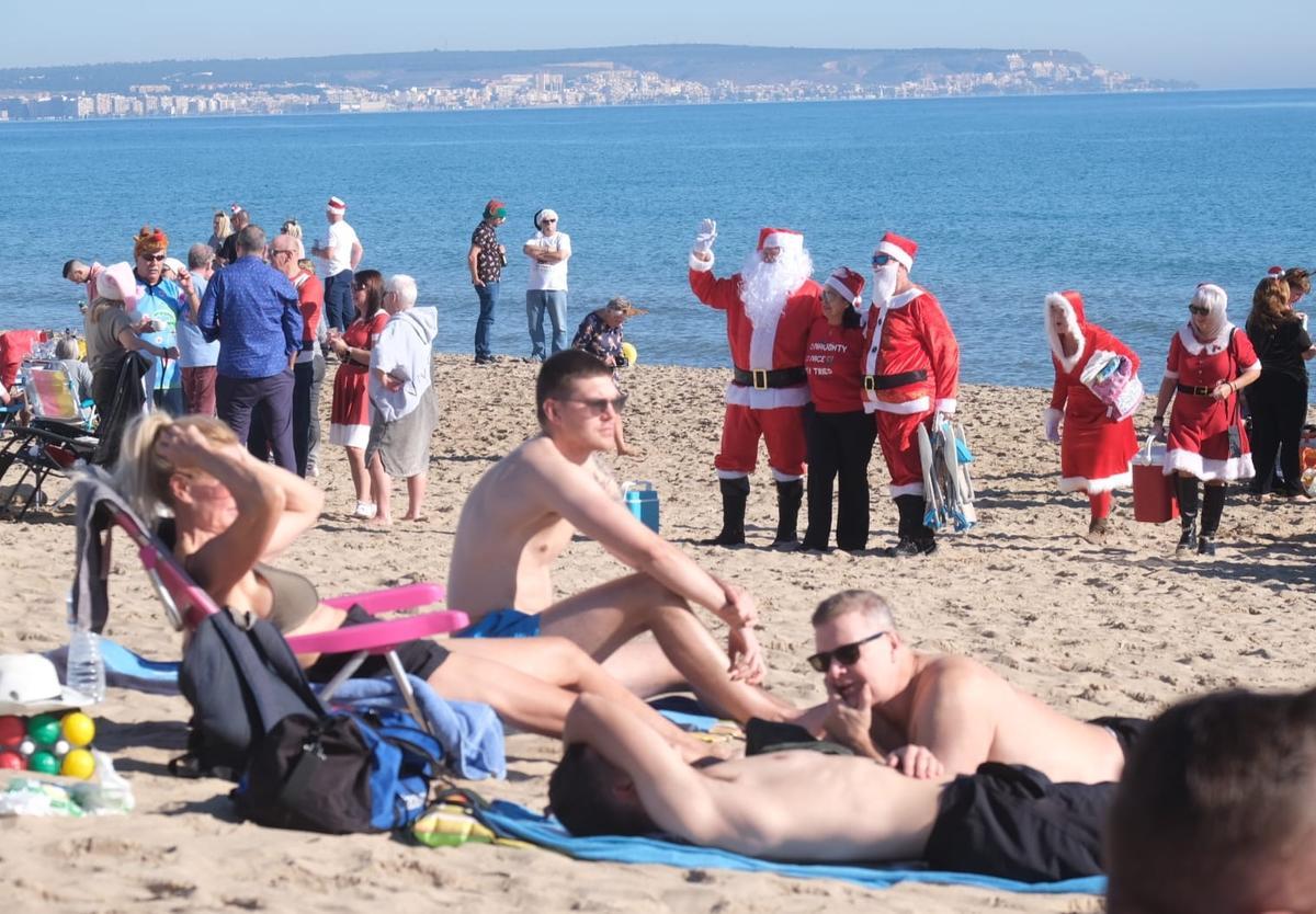 En la playa de La Marina, varias personas vestidas de Papa Noel.