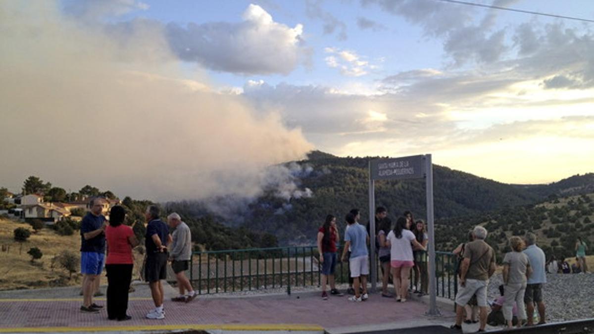 Varias personas miran desde la vía del tren el incendio de Valdemaqueda y Robledo de Chavela, cerca de Madrid.