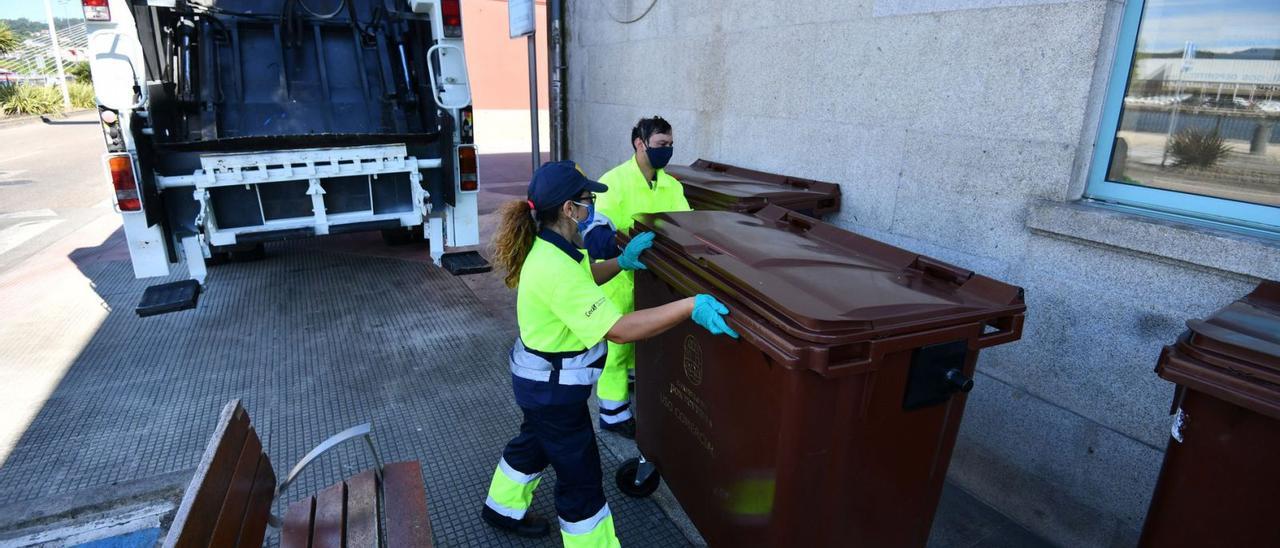 Dos operarios recogen un contenedor marrón en el que se deben ya depositar los biorresiduos en Pontevedra. |   // GUSTAVO SANTOS