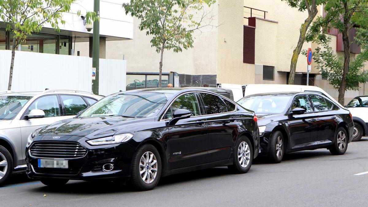 Dos coches de la empresa Uber esperan en doble fila a sus clientes.