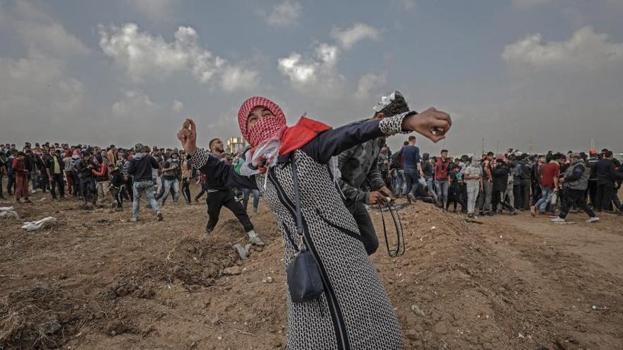 Una mujer palestina lanza piedras durante las protestas en Gaza..