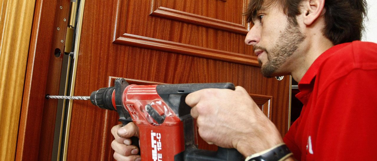 Un empleado de una empresa de seguridad, instalando una puerta blindada.