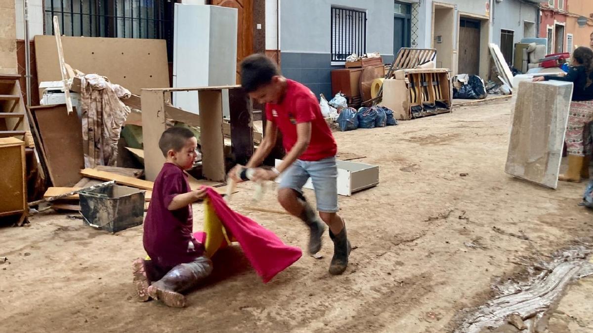 Los pequeños Javier, con el capote, y Blai, que hace de toro, en las calles de Algemesí tras la DANA.