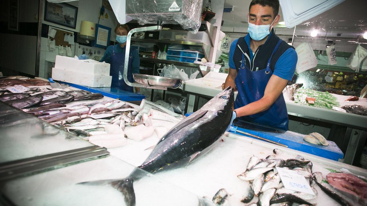 Un pescadero con un bonito del norte en su mostrador.