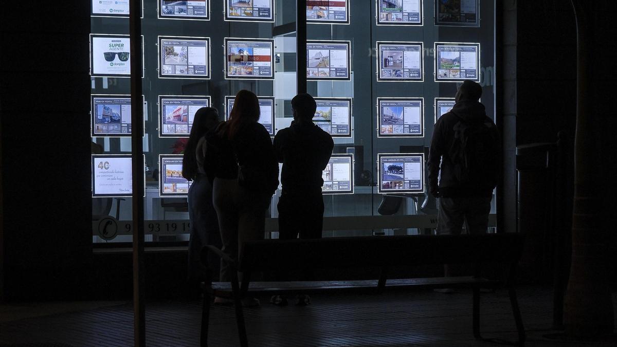 Varias personas miran las ofertas de una inmobiliaria.