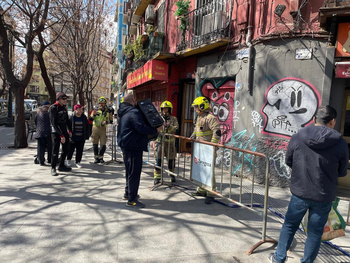 Un vecino recoge su ordenador de manos de los bomberos.